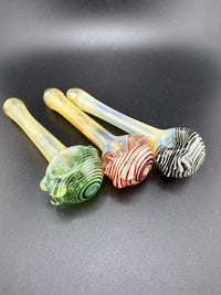 Handcrafted fumed lined hand pipes in green, red, and black designs, showcasing vibrant colors and durable glass.