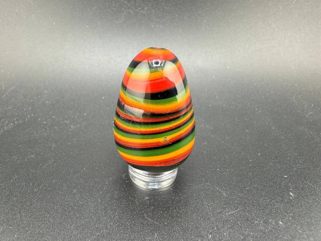 Colorful handcrafted Paulson Pieces Easter Egg Marble in vibrant stripes of red, black, yellow, and green.