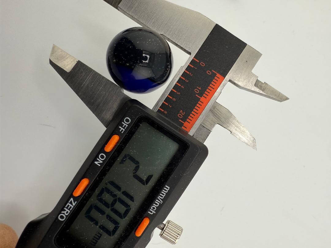 Measuring a 20mm blue marble slurper top with digital calipers for accurate sizing.