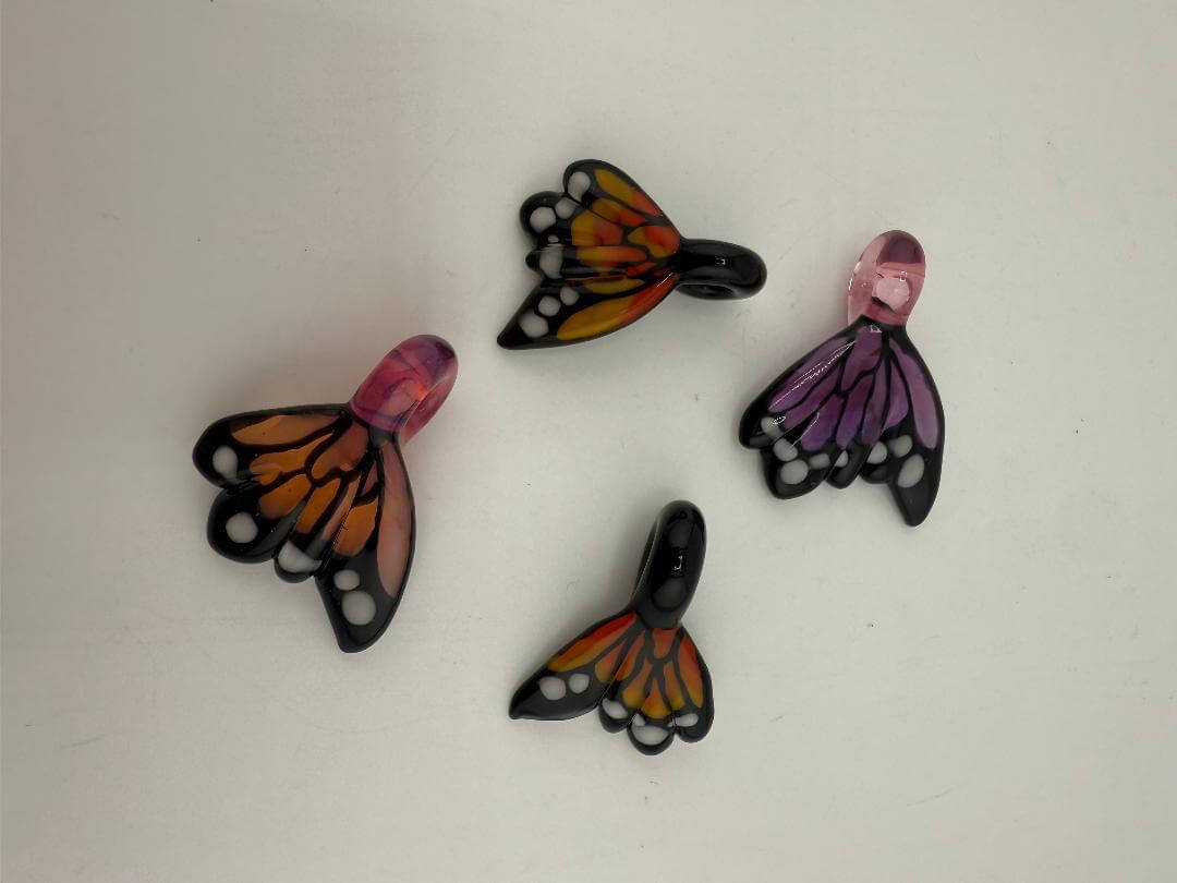 Colorful butterfly pendants in orange, pink, and purple, showcasing intricate designs ideal for jewelry crafting.