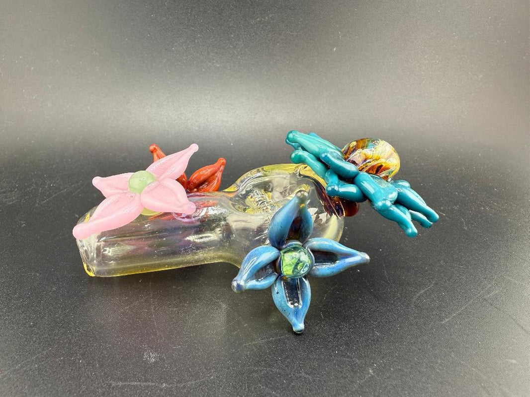 Pablos Glass Flower Hand Pipe featuring colorful glass flowers in pink, blue, and red on a transparent base.