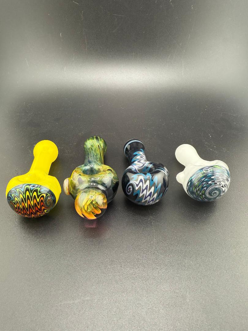 Four handcrafted glass pipes showcasing vibrant colors and unique designs on a black background.