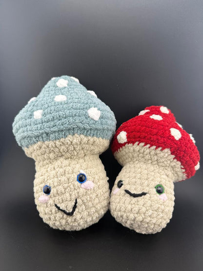 Adorable crochet mushroom plushies in blue and red, featuring cute smiles and polka dots, perfect for decor or gifts.
