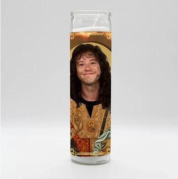 Bobbyk Saint Candles featuring a playful design of a smiling figure in traditional attire on a tall white prayer candle.