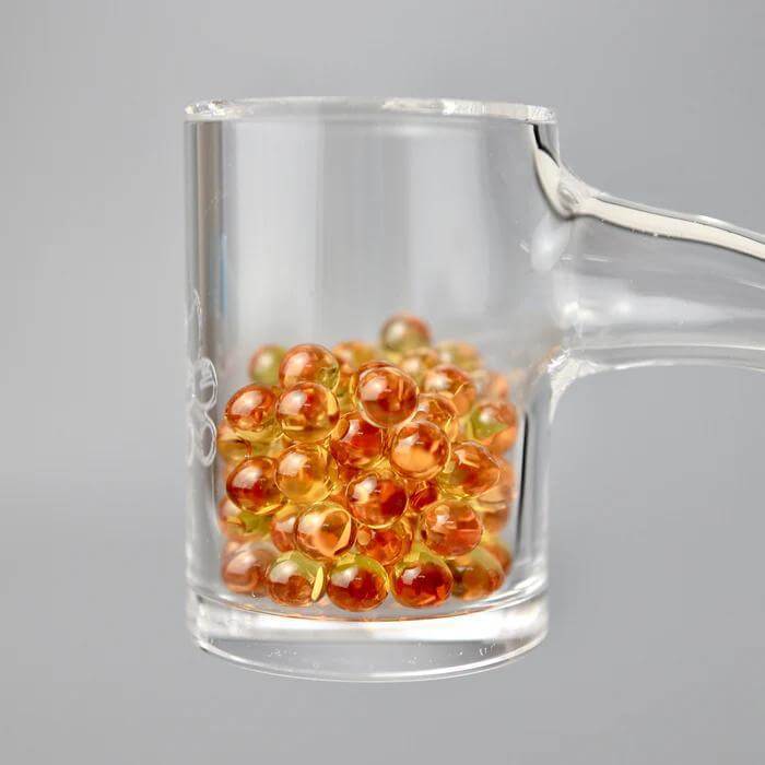 Ruby Pearl Co Yellow Sapphire Terp Pearls in a glass container for enhanced dabbing performance and flavor.