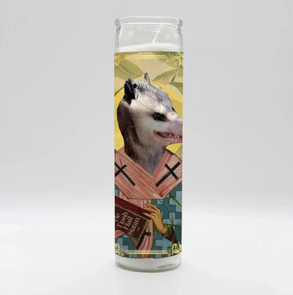 Tall candle featuring unique parody art from the BOBBYK Saint Candles collection, showcasing an opossum with a religious theme.