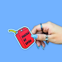 Person holding a BBB Sticker | Fueled By Spite, featuring a red gas can design with text.
