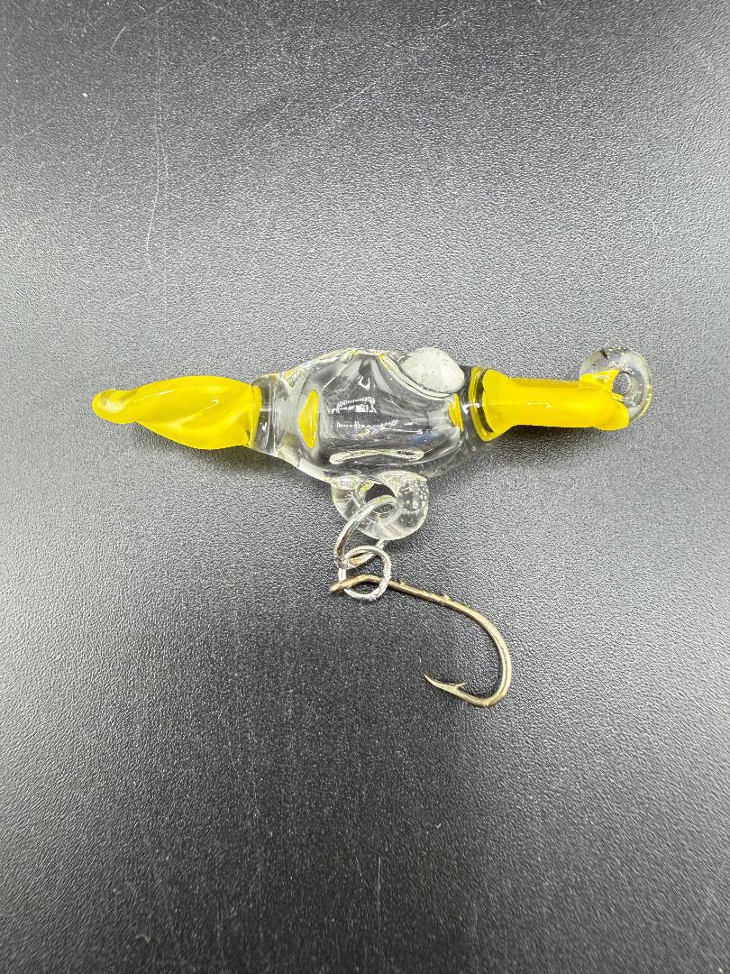 Handcrafted Paulson Pieces glass fishing lure with yellow accents and metal hook on a dark background.