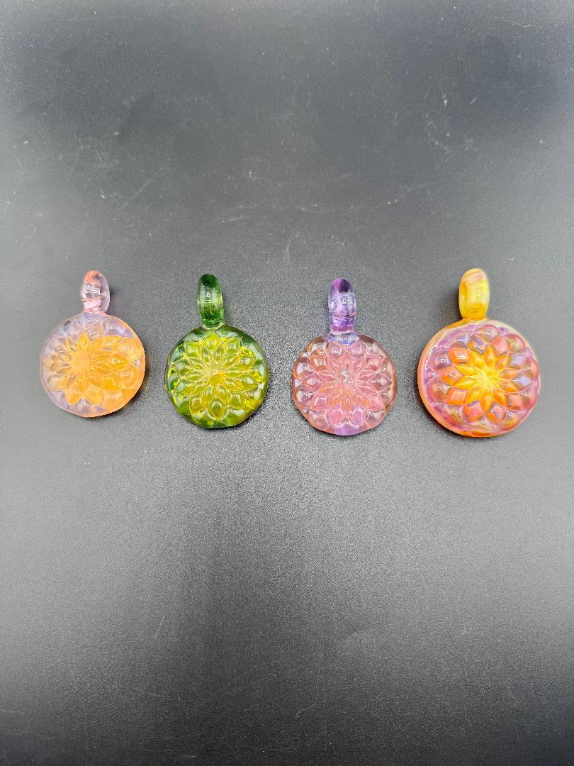 Colorful handcrafted glass pendants in various shapes and colors, showcasing intricate designs and craftsmanship.