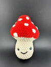 Adorable crochet mushroom plushy with red cap and white spots, featuring a smiling face, perfect for cuddling.