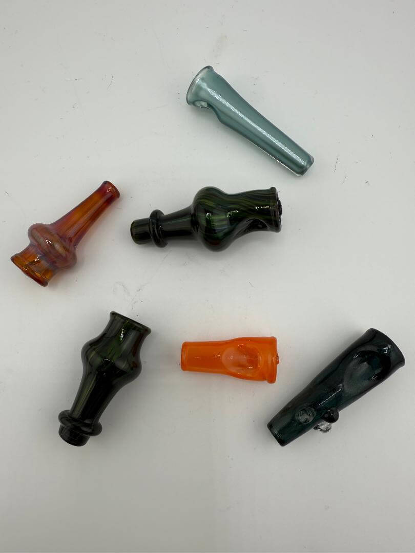 Collection of colorful glass pivot tops in various shapes, including brown, green, and more.