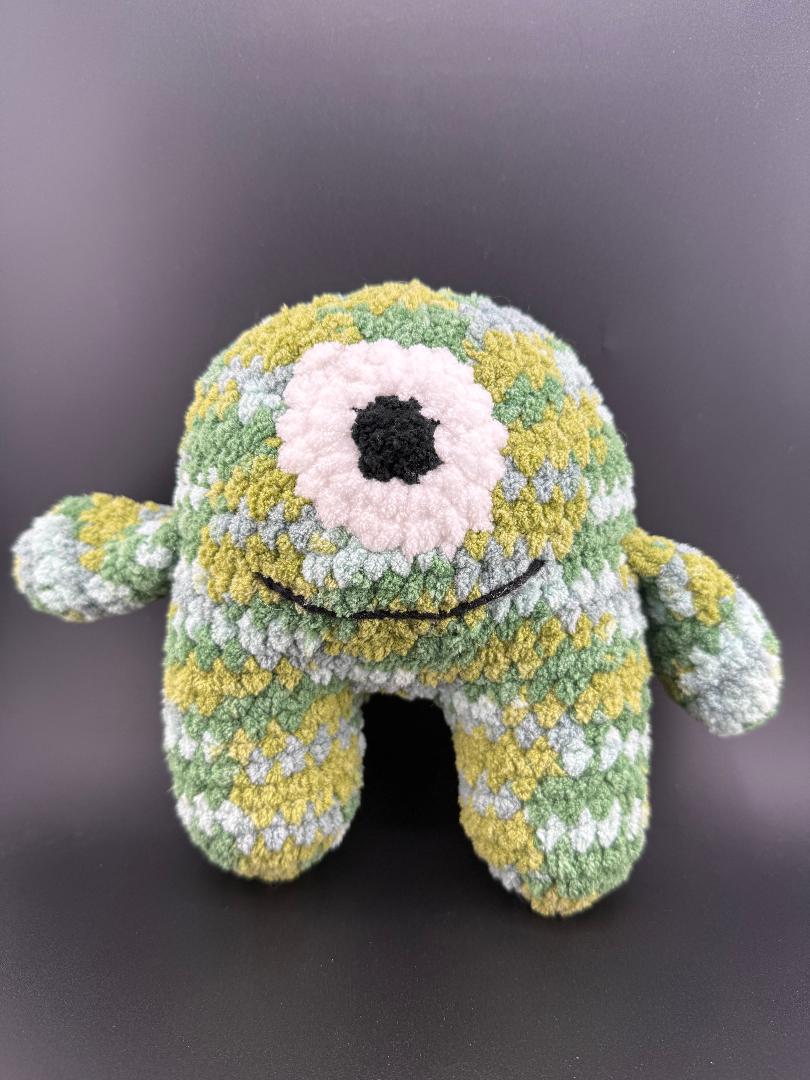 Crochet one-eyed monster plush toy in green and gray, cute and handmade for kids and collectors.