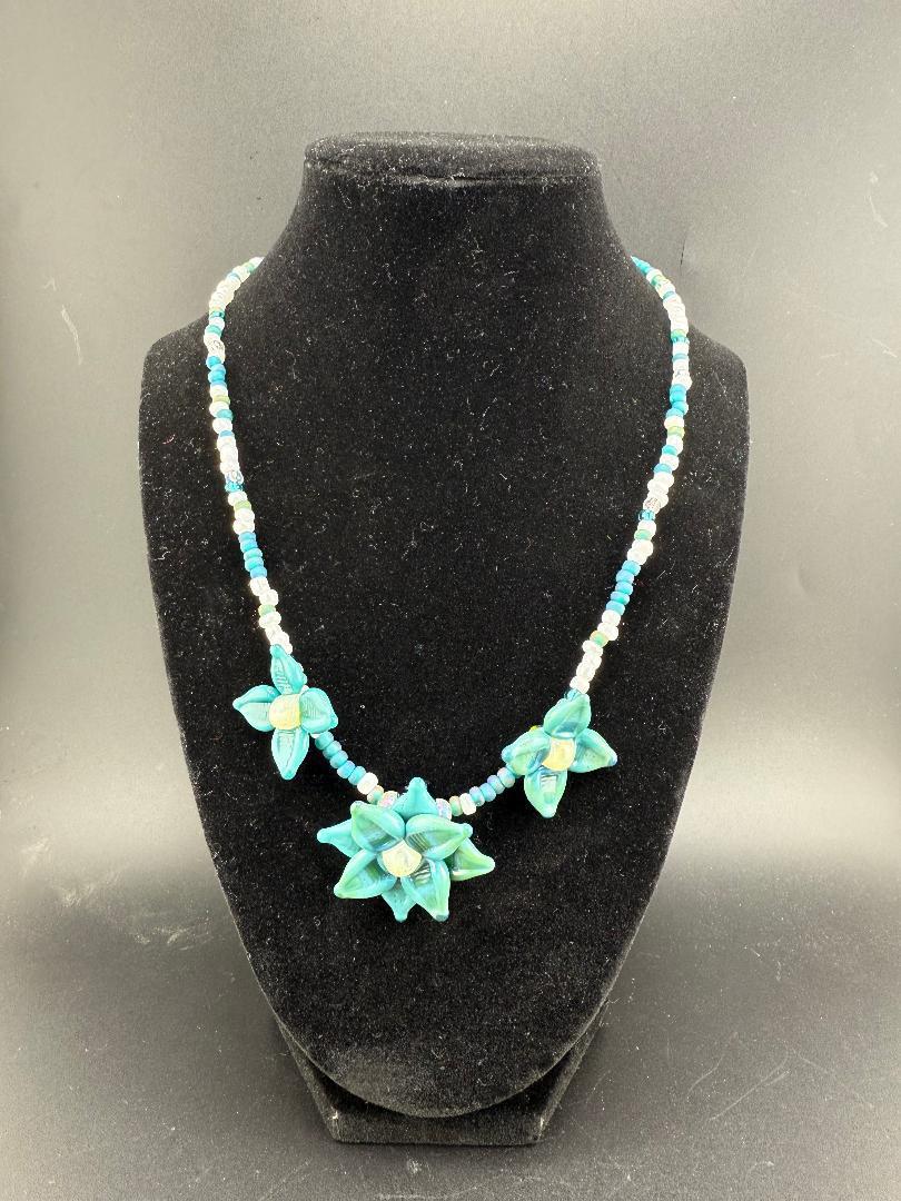 Pablos Glass Flower Beaded Necklace featuring handmade turquoise flower beads on a black display.