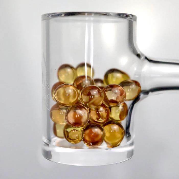 Ruby Pearl Co Yellow Sapphire Terp Pearls in a glass dish, showcasing their premium quality and dabbing performance.