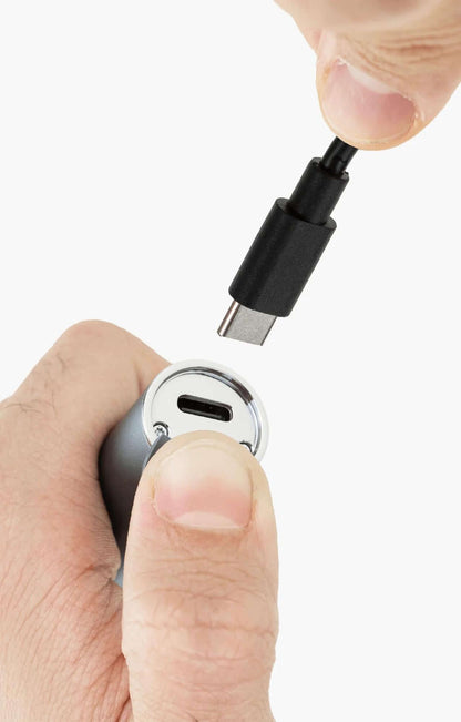 Person's hand connecting USB-C cable to Puffco Pivot Mobile Vaporizer for charging.