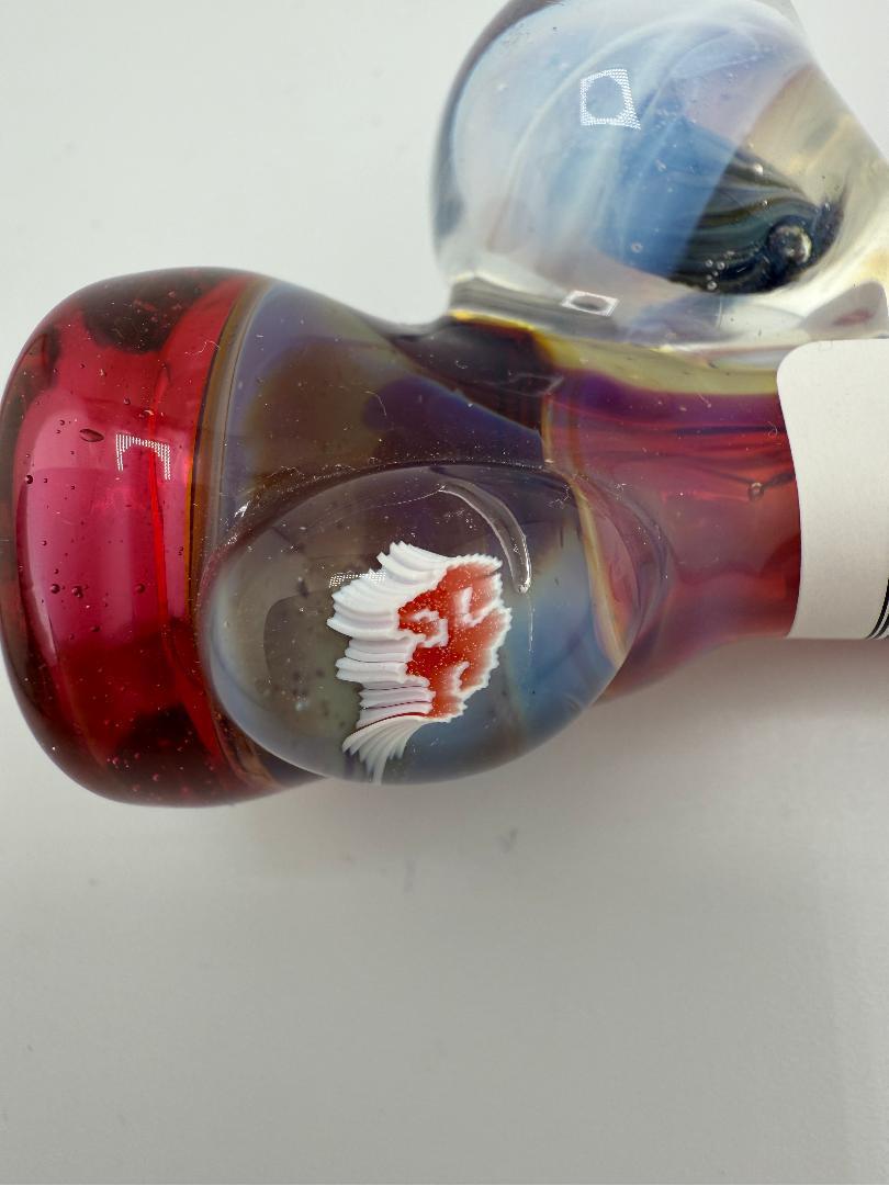 Close-up of a Tuck Glass pink and blue one-hitter pipe showcasing vibrant hues and intricate design details.
