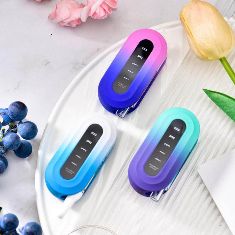 Three Dazzleaf DKEii 510 batteries in vibrant colors on a tray with flowers and grapes, showcasing ergonomic design.