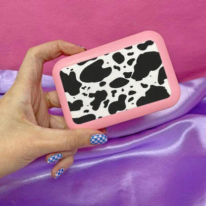 A Shop Of Things Mini Stash Box - Moo held in hand, featuring a cow print design against a pink background.
