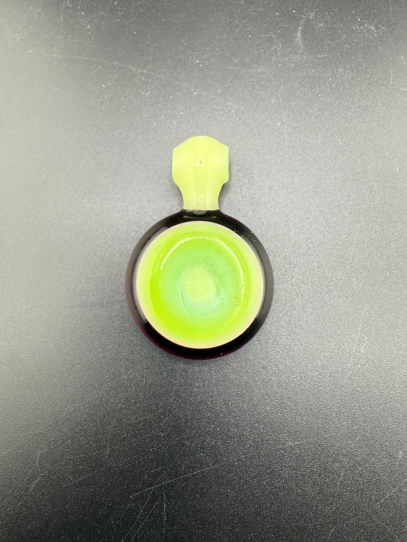 Close-up of a Mcdoogle Glass pendant featuring green and black swirls, handcrafted in Spokane, WA.