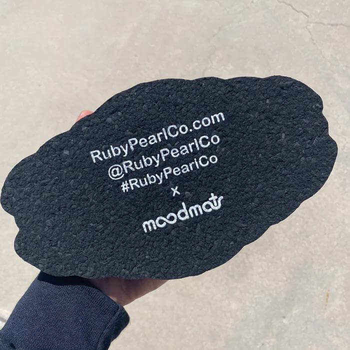 Underneath view of the Ruby Pearl Co Mood Mat showing brand details and logo, made from recycled wetsuits.