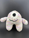 Crochet one-eyed monster plush toy in pastel colors, featuring a black smile and soft, fuzzy texture.