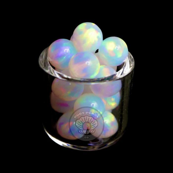 Ruby Pearl Co 6mm White Opal Terp Pearls displayed in a glass holder, showcasing their opalescent shine.