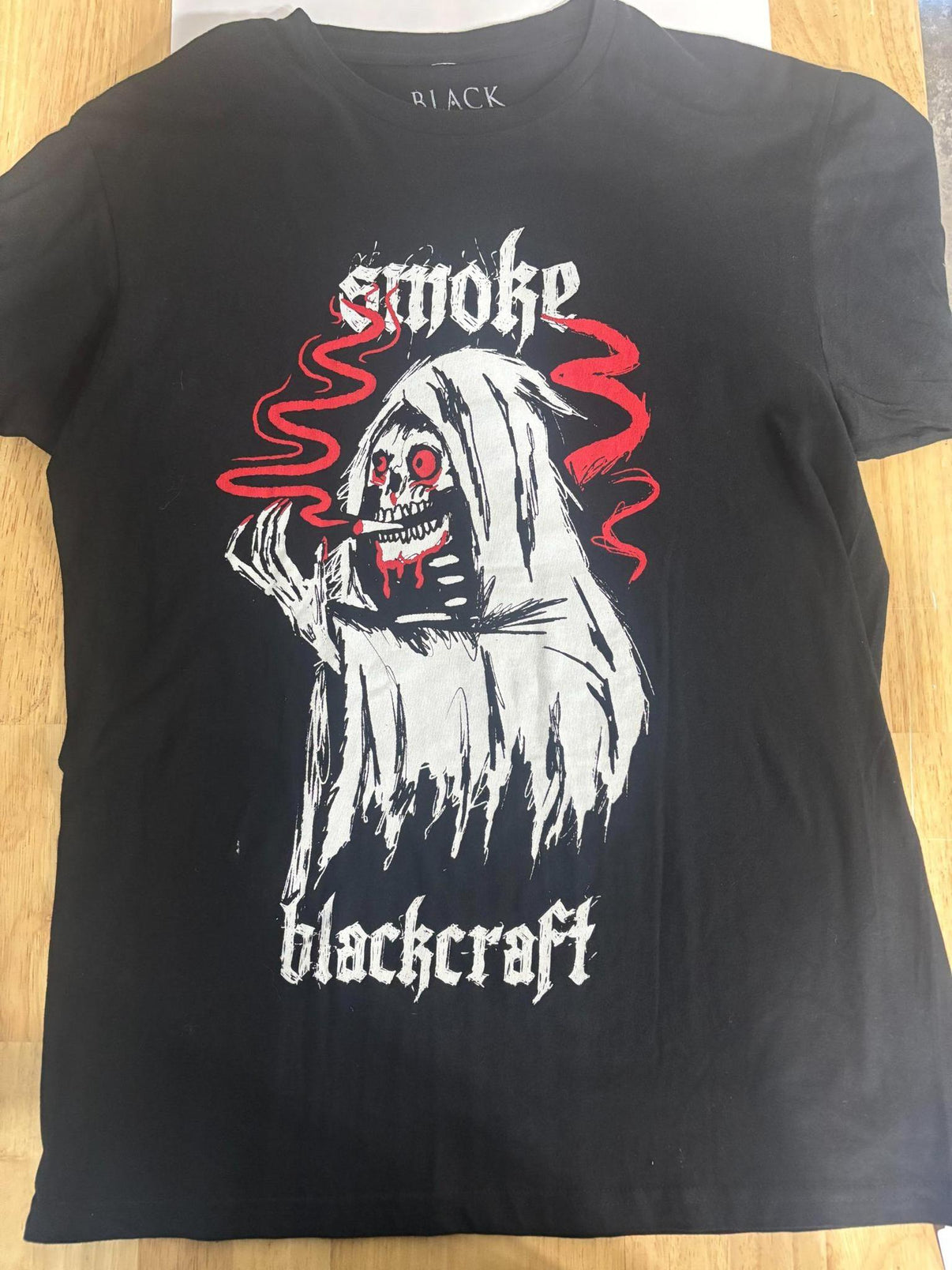 BlackCraft Cult T-shirt featuring a haunting design with smoke and a spooky character in bold colors.