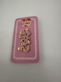 Bobby Pins Co. Enamel Pin - Heart Panther displayed on a pink backing card, featuring a gold-colored heart pattern.
