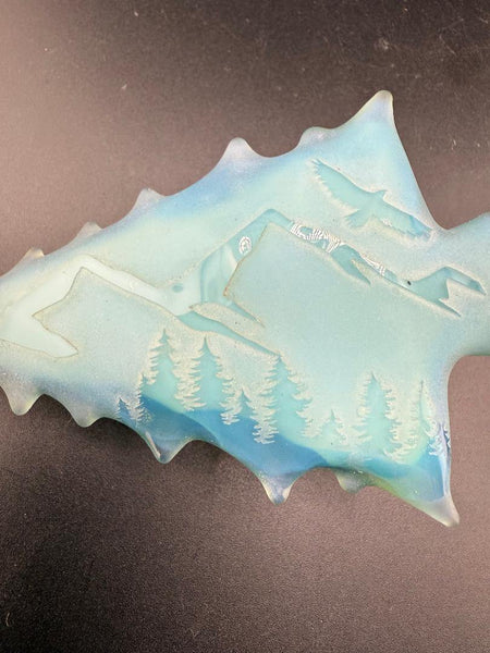 Brando Glass Belt Buckle - Light Blue Sandblasted Arrowhead w/ Mountain & Forest Scene, featuring detailed carvings.