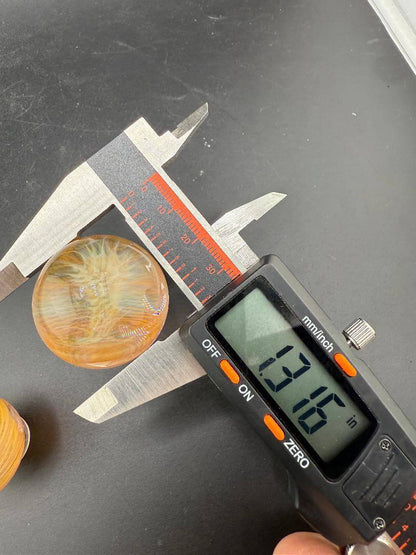 Brando Glass Gold Fumed Marble 1.3" being measured with calipers for precision.