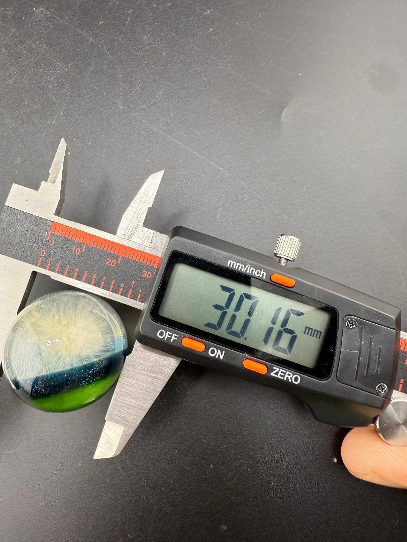 Brando Glass Marble - 30mm Fumed Implosion measured at 30.16mm using calipers on black surface.