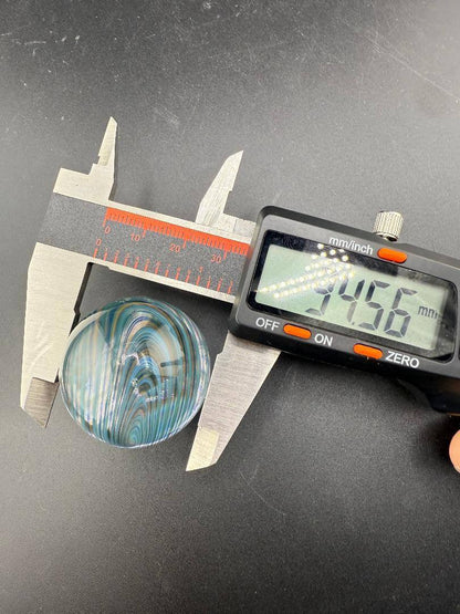 Brando Glass Marble - 34mm Blue & Teal Line Work Over Clear Marble being measured with calipers.