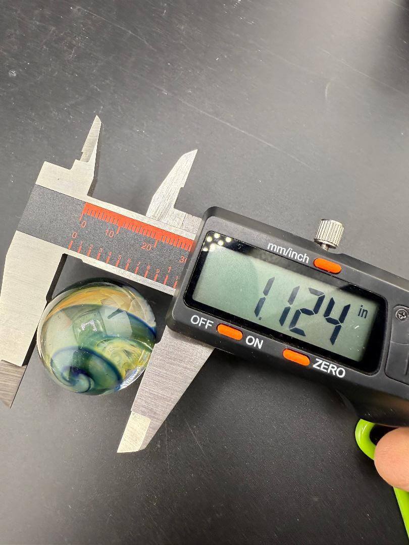 Brando Glass Marble - Double Vortex Approx. 1.15" being measured with calipers showing 1.124 inches.