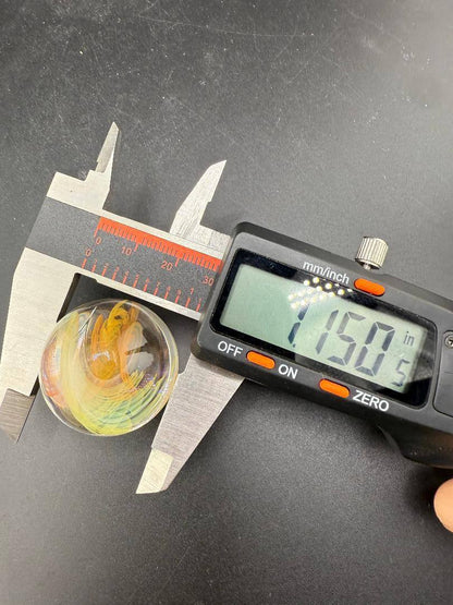 Brando Glass Marble - Fumed Implosion being measured at 1.150 inches showcasing its vibrant color and craftsmanship.