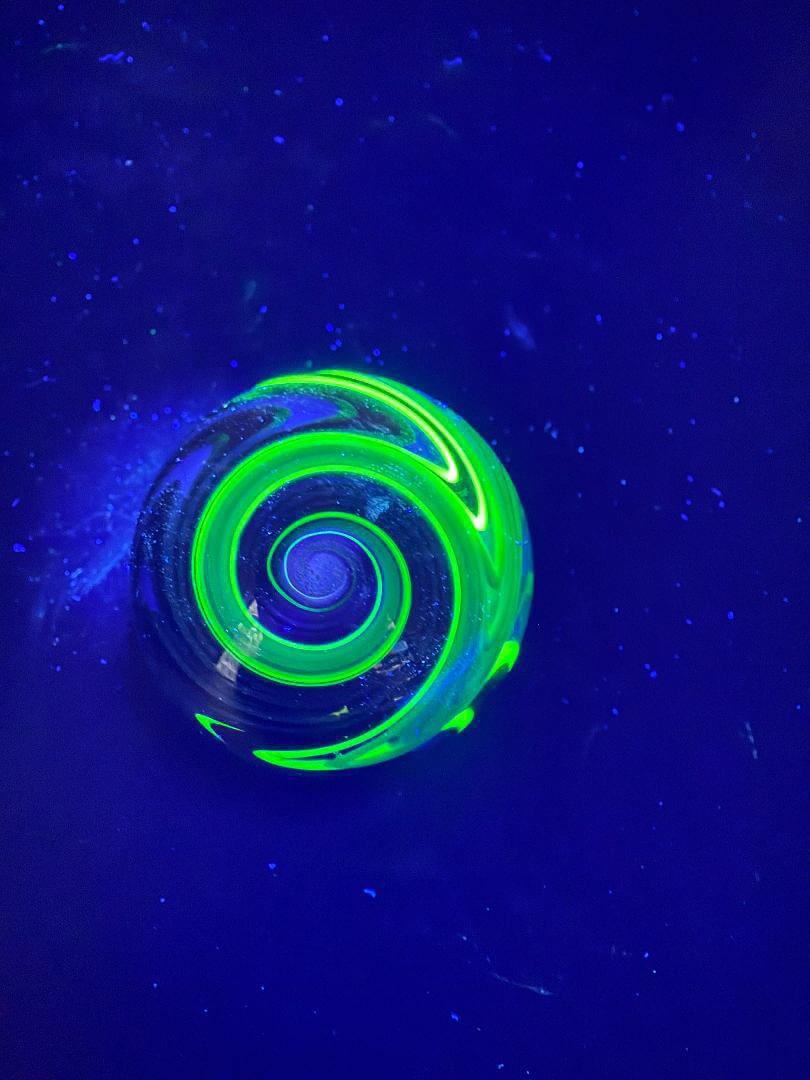 Brando Glass Marble - UV Green Fully Line Worked Twist 1.8" under UV light, showcasing intricate spiral design.