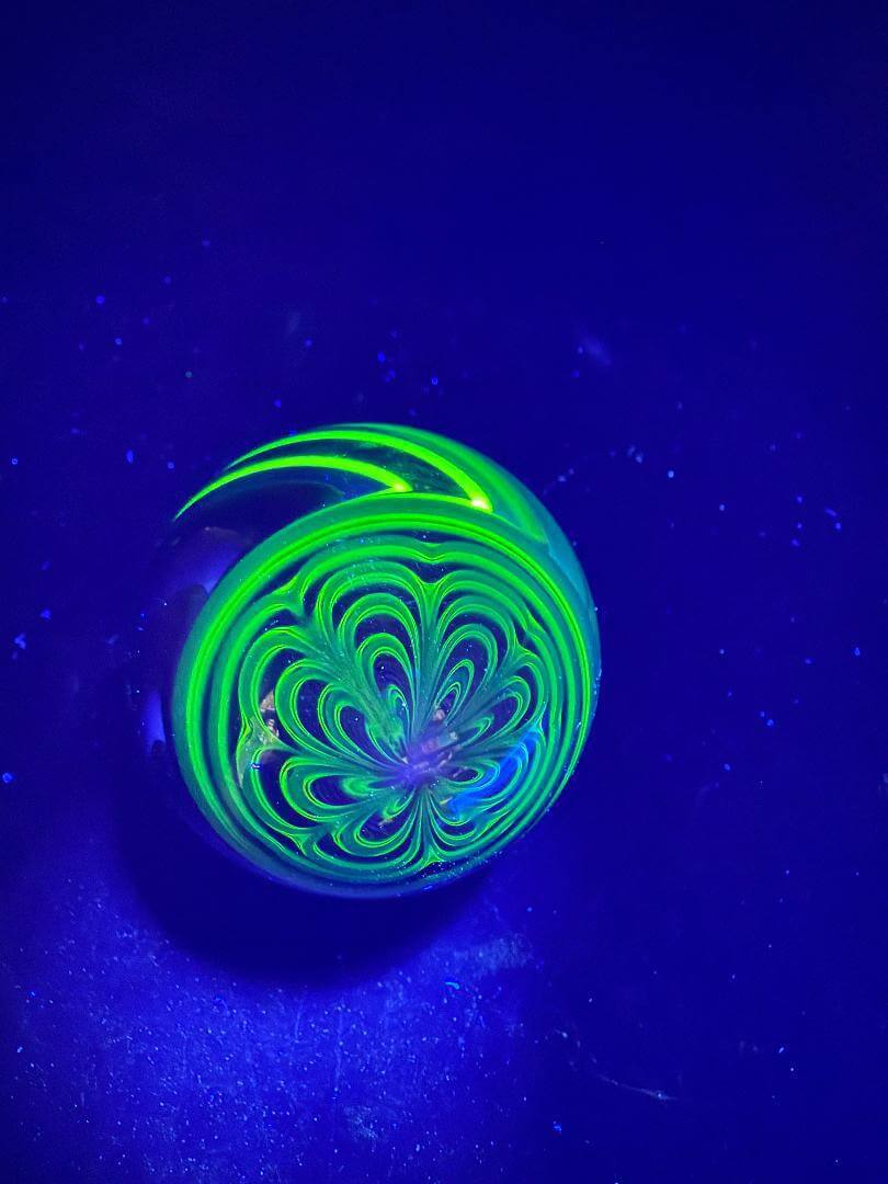 Brando Glass Marble - UV Green Fully Line Worked Twist 1.8" under UV light showcasing intricate spiral design.