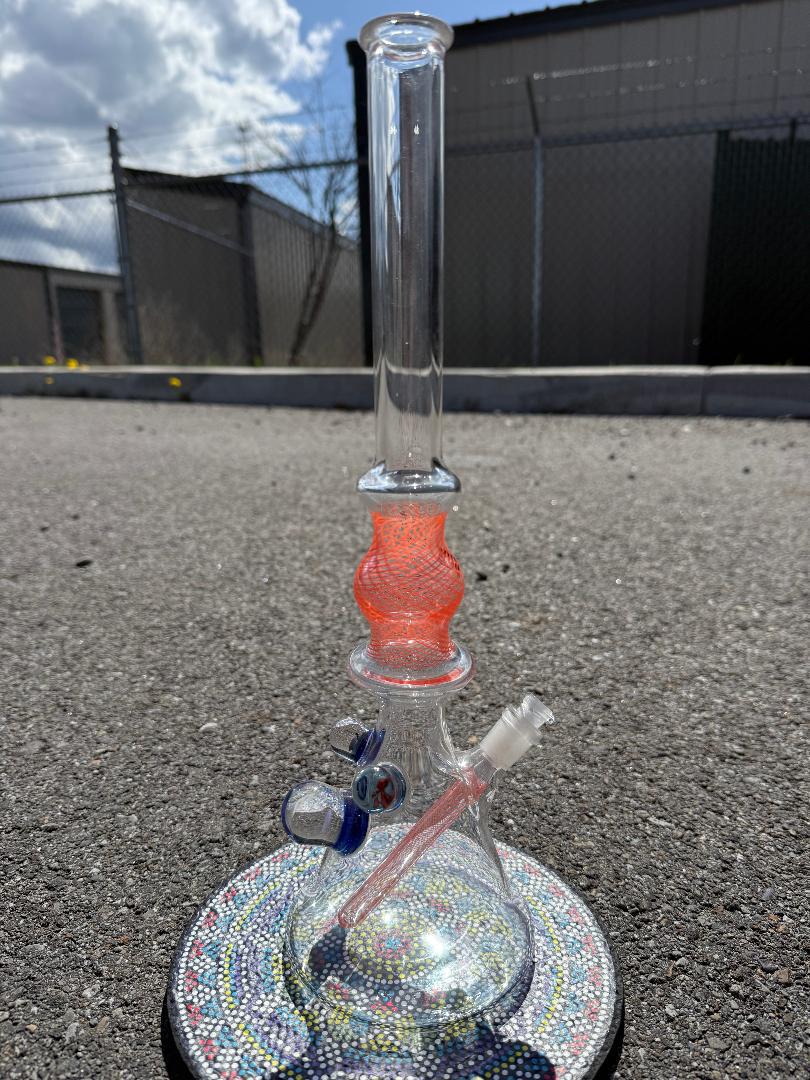 Brando Glass Orange Reticello Pokémon Milli Tube 10mm on asphalt, showcasing vibrant design and intricate details.