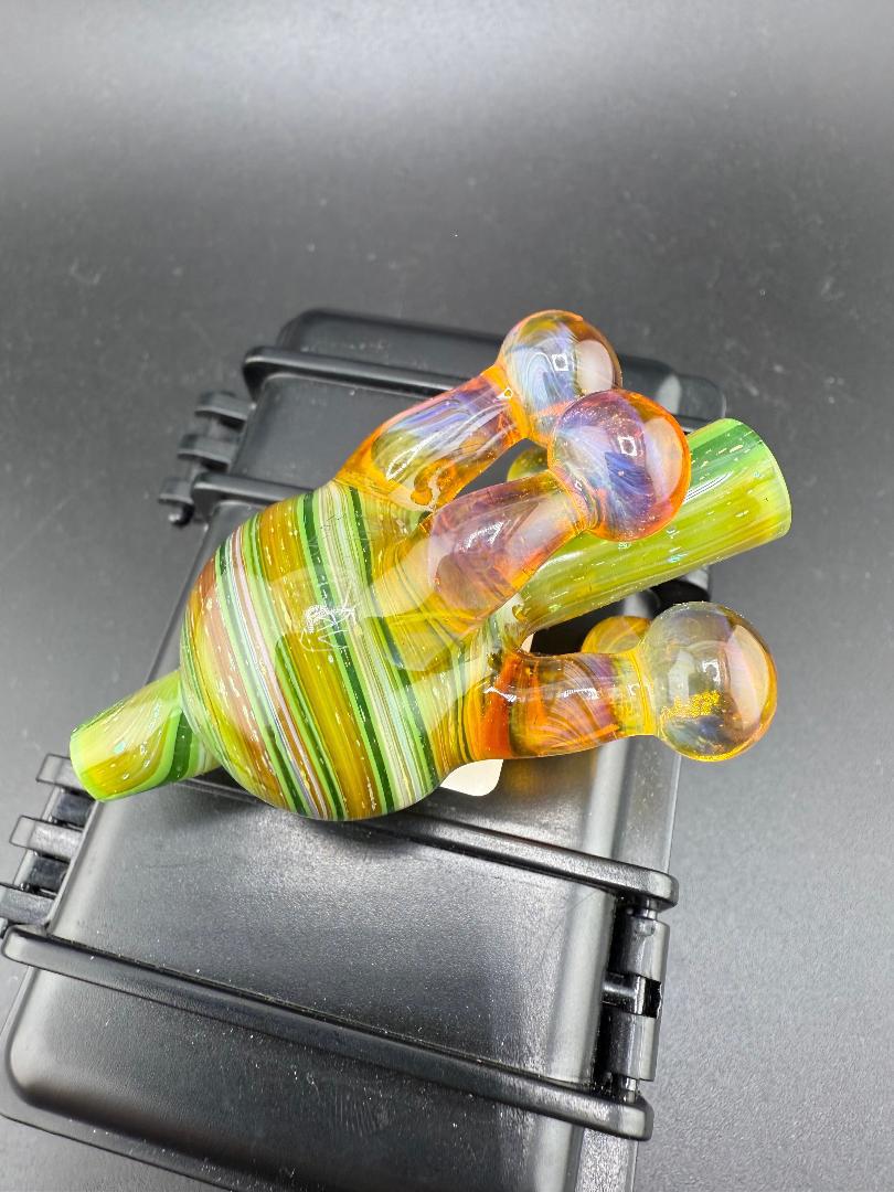 Colorful handcrafted glass bubble cap with striped design on a black surface.