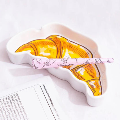 Canna Style Ashtray - Croissant with a pink paper resting in the croissant-shaped tray.
