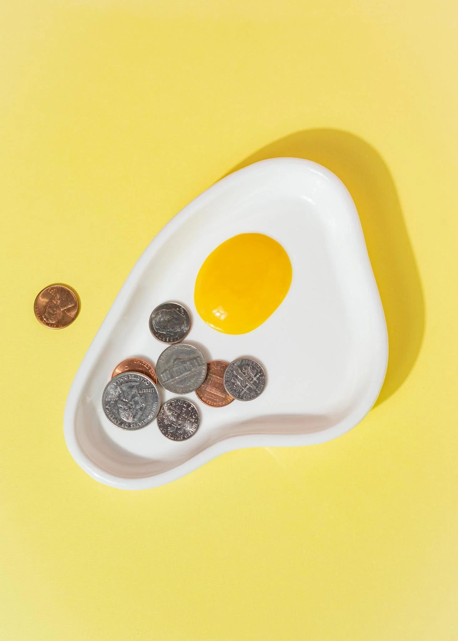 Canna Style Ashtray - Egg features a playful egg-shaped design with coins on a yellow background.
