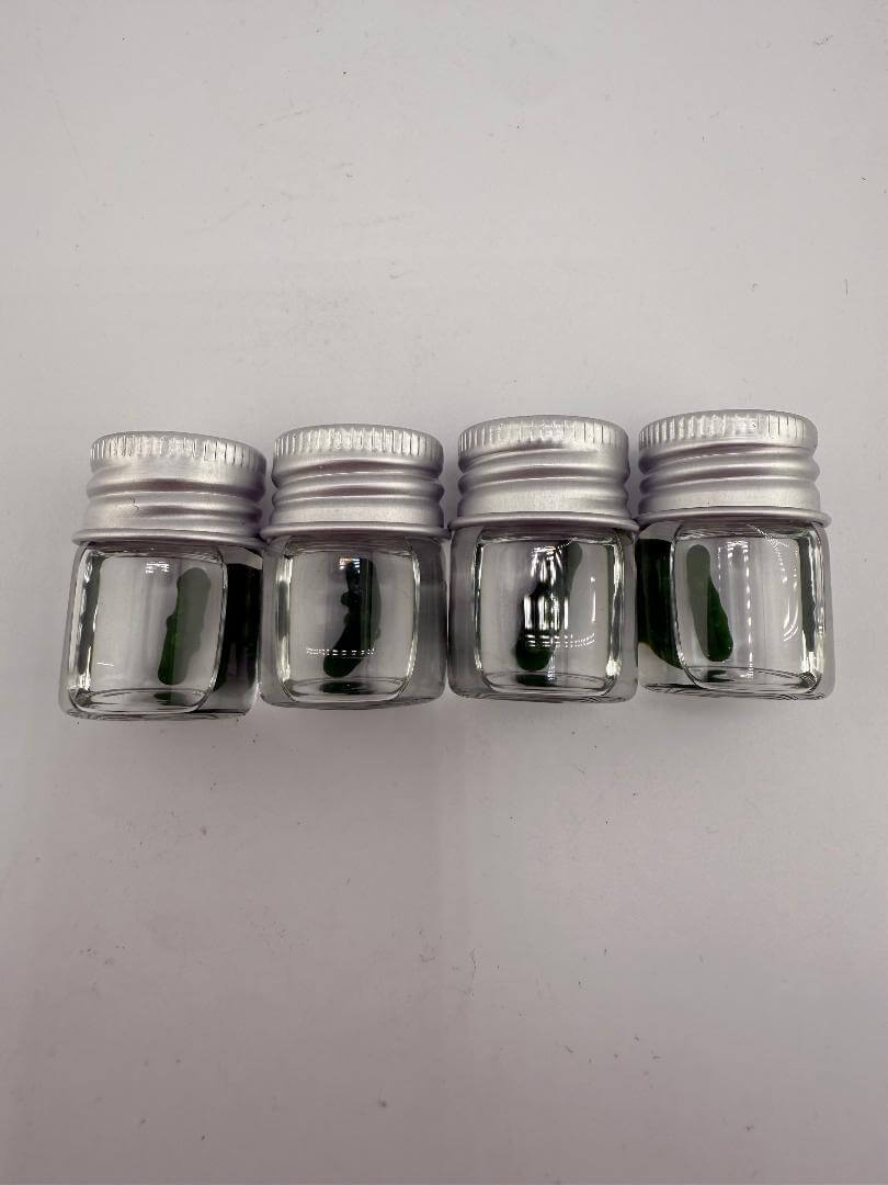 Four clear glass jars with silver lids, ideal for storing herbs or extracts, displayed side by side.