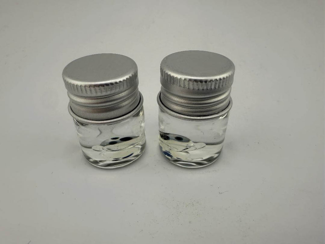 Two glass jars with metal lids, filled with clear liquid, suitable for storage or as part of a dab setup.