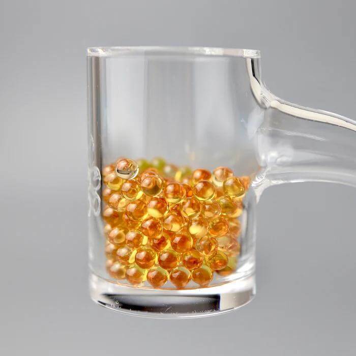 Ruby Pearl Co Yellow Sapphire Terp Pearls in glass dish, premium quality for enhanced dabbing performance.