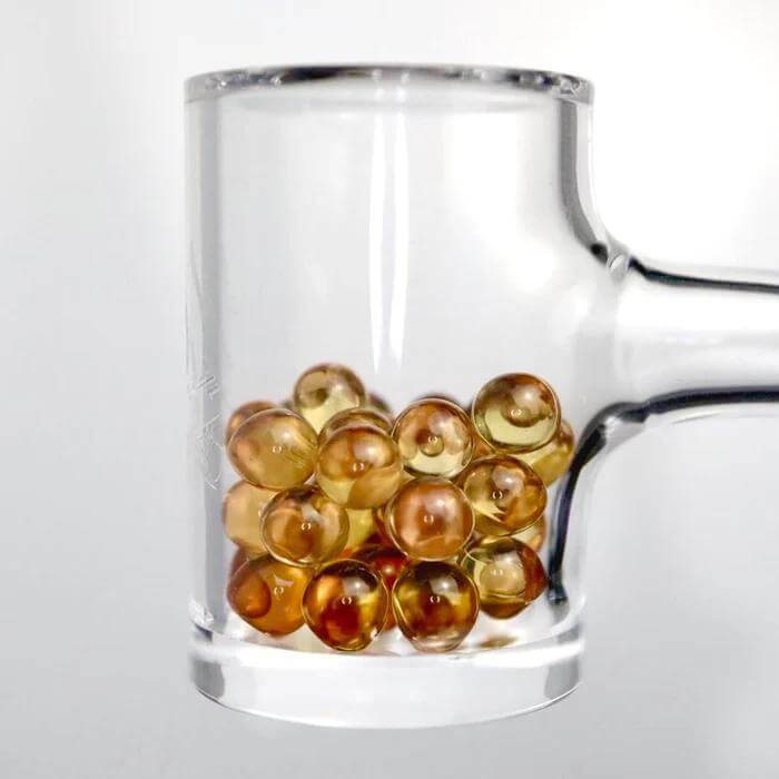 Ruby Pearl Co Yellow Sapphire Terp Pearls in a clear banger for enhanced dabbing experience and flavor retention.