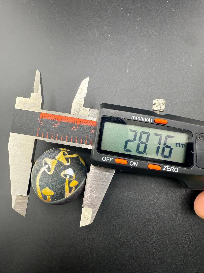 Danny W Glass Marble - 28mm Carved Mushrooms measured at 28.76mm with calipers on a black background.