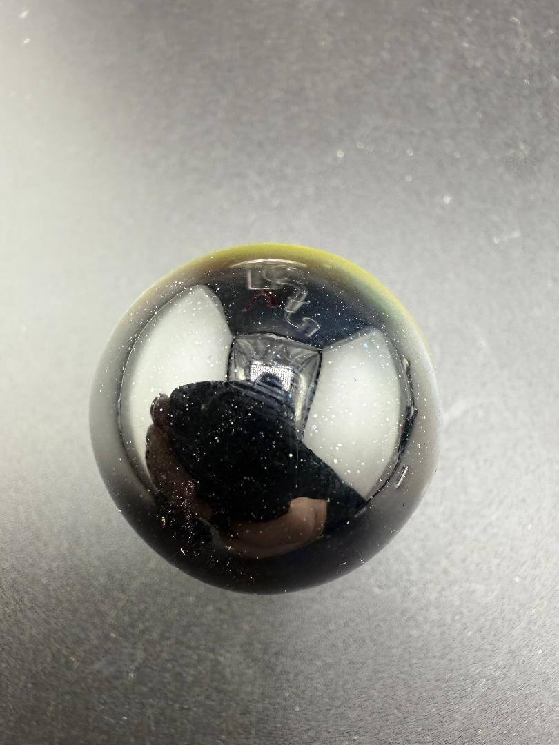 Danny W Glass Marble - 29mm Multi Layered Yellow & Orange, featuring a glossy black surface with reflective qualities.