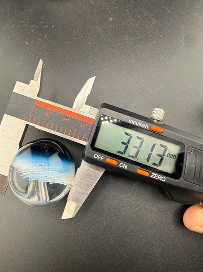 Danny W Glass Marble - 33mm White Implosion measuring 33.13mm with calipers on a black background.