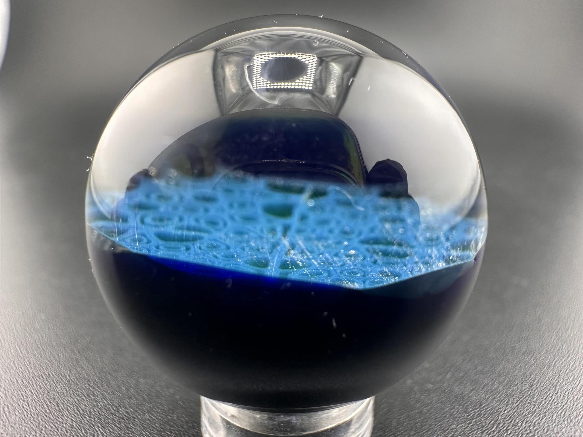 Domer Glass Marble - Blue Mitosis Millie Chip Stack UV displayed on a stand, showcasing intricate blue design.