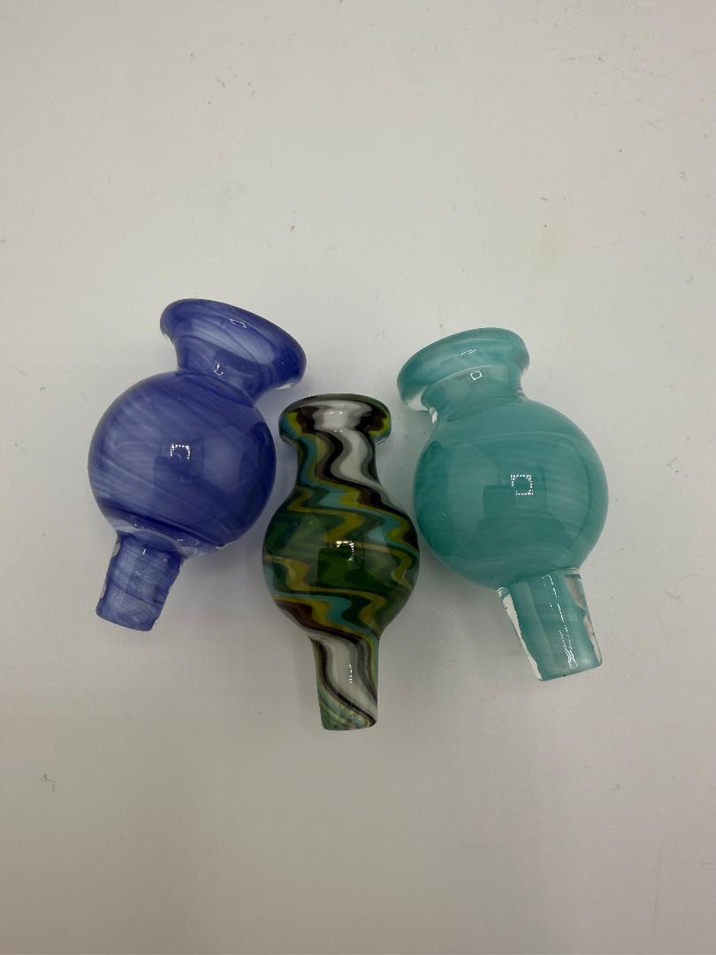 Three handcrafted Lylo Glass Carb Caps in blue, teal, and a green wig wag design for quartz bangers.