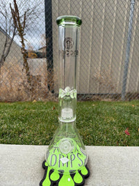 Encore Glass 16" Matrix Perk Beaker 14mm 90° standing on grass next to green drip-themed coaster.